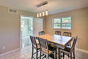 A dining area with a wooden table and chairs, a ceiling light fixture, and a window with a view of greenery. - Spacious Fort Worth Getaway < 4 Mi to Dtwn! (Fort Worth)