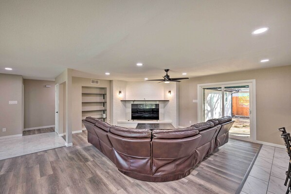 A modern living room with a large L-shaped sectional sofa, a flat-screen TV, and a ceiling fan. - Spacious Fort Worth Getaway < 4 Mi to Dtwn! (Fort Worth)