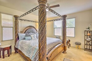 A four-poster canopy bed with a wooden frame and intricate carvings, a wooden headboard, and a small stool with a fluffy cushion. - Glendale Retreat: Walk to State Farm Stadium! (Glendale)