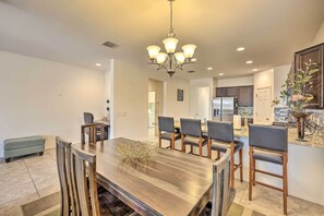 A modern kitchen with a central island, dark wooden dining table, and bar stools. - Glendale Retreat: Walk to State Farm Stadium! (Glendale)