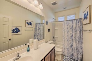 A bathroom with a white sink, a mirror, a toilet, and a shower area. - Glendale Retreat: Walk to State Farm Stadium! (Glendale)
