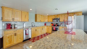 A modern kitchen with wooden cabinets, granite countertops, stainless steel appliances, and a red decorative metal rack. - 2 Mi to Lake Havasu State Park: Home w/ Pool! (Lake Havasu City)