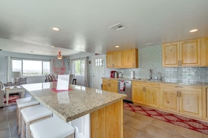 A spacious kitchen with granite countertops, wooden cabinets, and a red patterned rug. - 2 Mi to Lake Havasu State Park: Home w/ Pool! (Lake Havasu City)