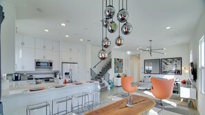 A modern kitchen with white cabinets, stainless steel appliances, and a central island with bar stools. - Modern Oasis w/ Mtn-view Pool Deck - Walk Downtown (Palm Springs)