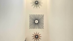 A narrow hallway with three wall-mounted clocks of different styles. - Modern Oasis w/ Mtn-view Pool Deck - Walk Downtown (Palm Springs)