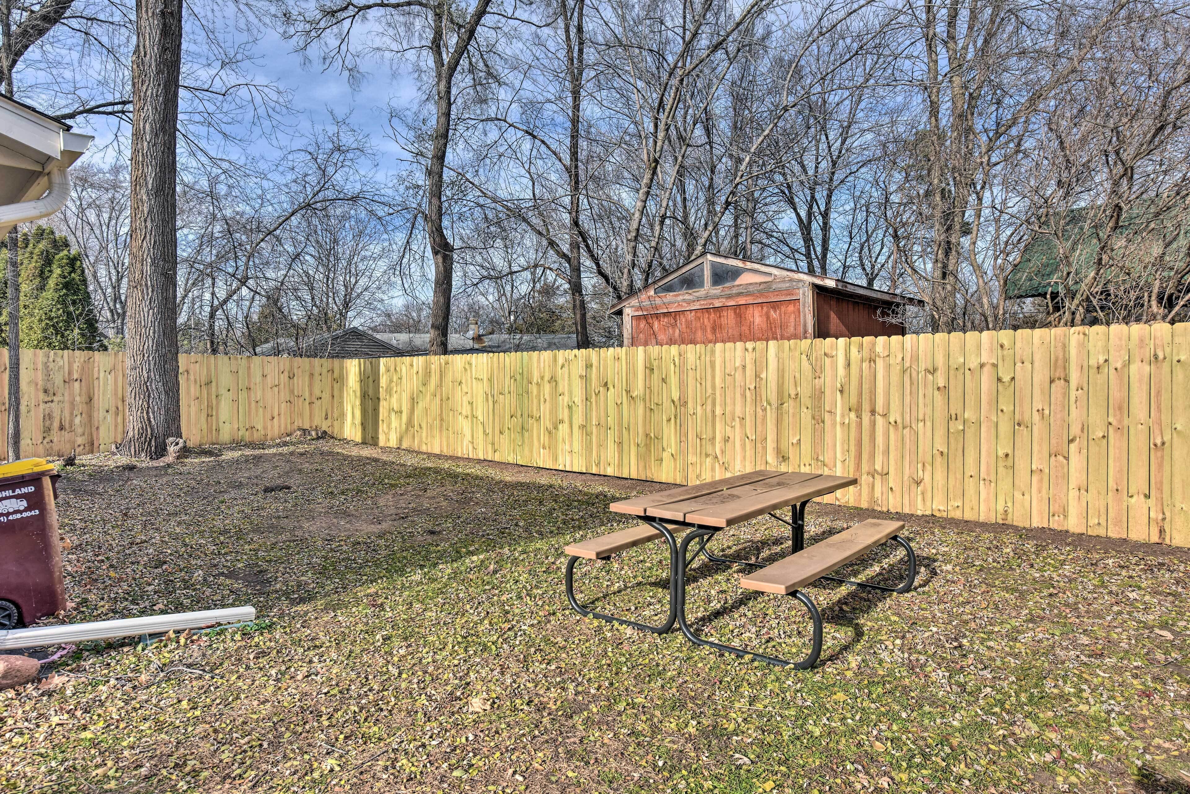 A backyard with a wooden fence, a picnic table, and a shed.