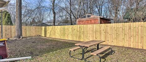 A backyard with a wooden fence, a picnic table, and a shed.
