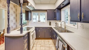 A kitchen with dark cabinets, a white countertop, and a window above the sink. - Walk to Lake Michigan & Dtwn: Coastal Grand' (Ludington)