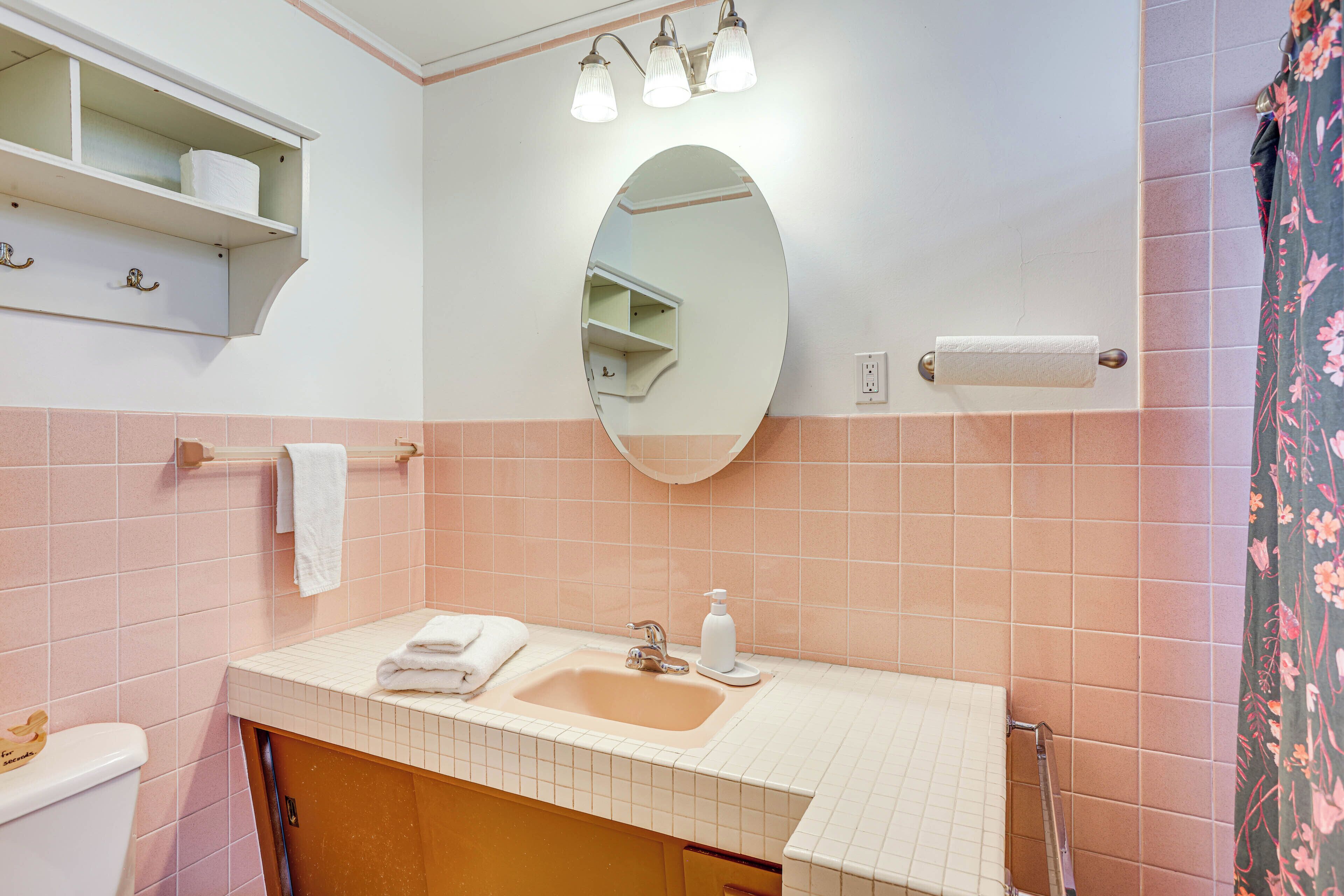 Un baño con lavamanos, espejo y perchero para toallas.