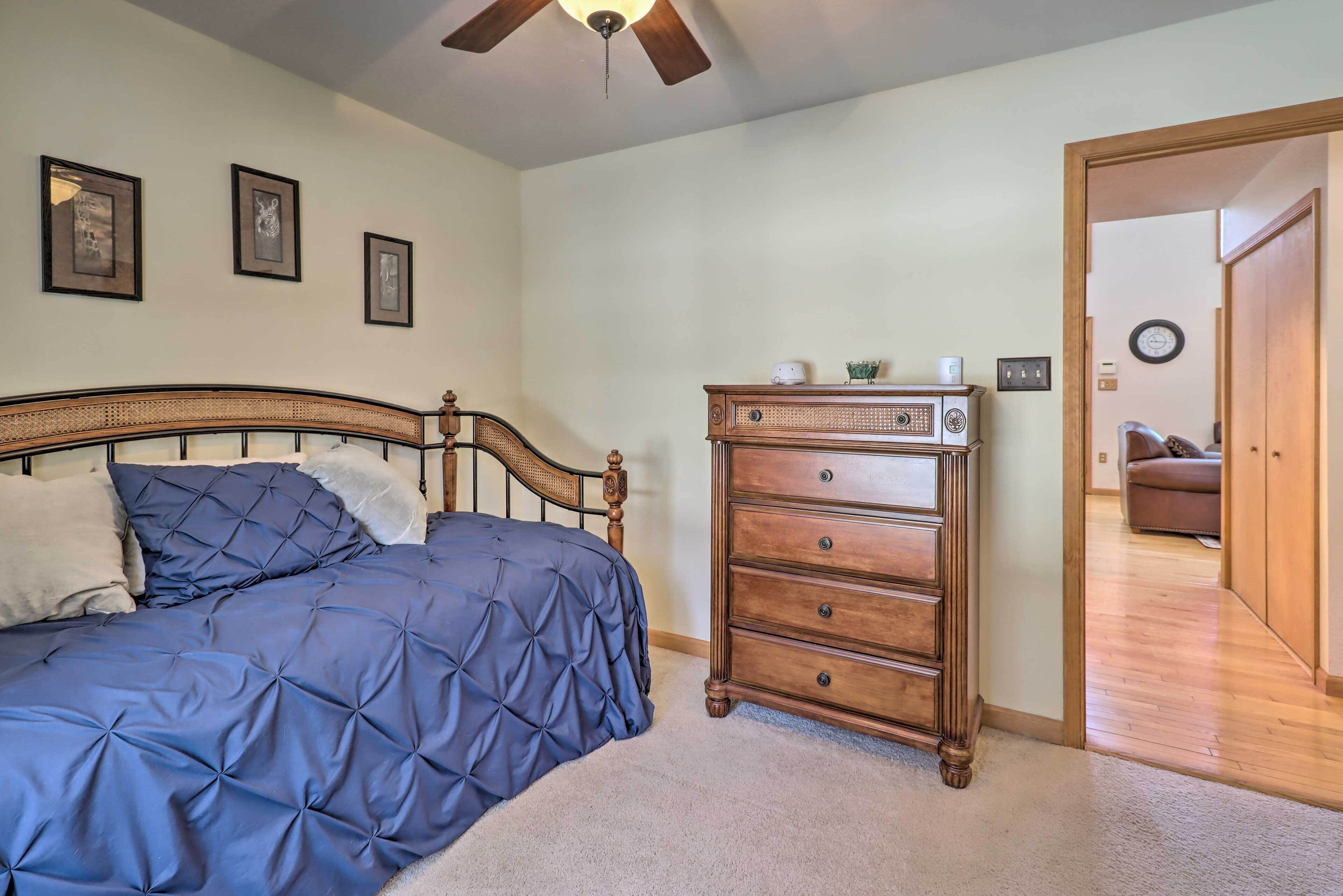 A bedroom with a bed, a dresser, and a ceiling fan.