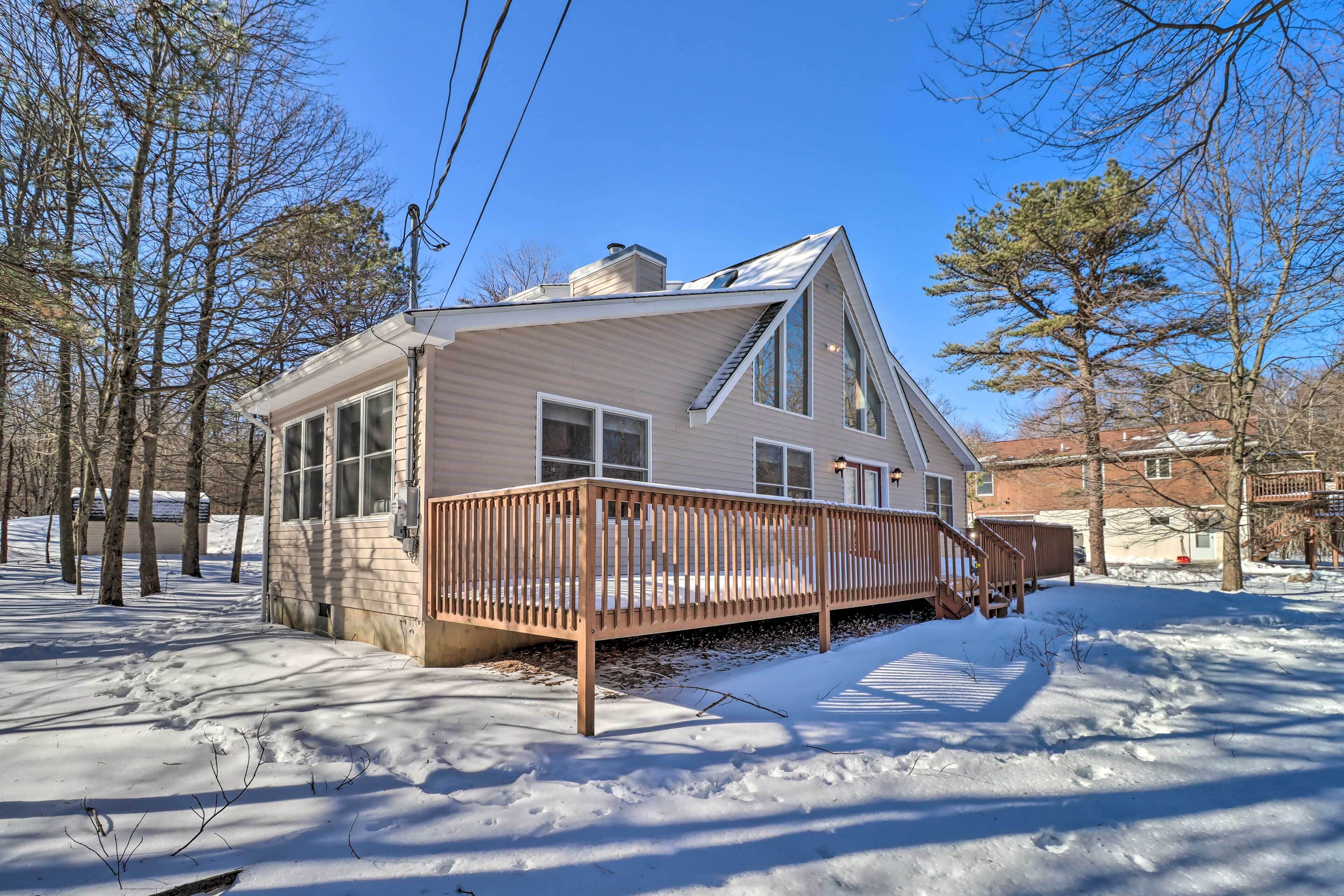 Une maison à deux étages avec une terrasse en bois, de grandes fenêtres et une cheminée.