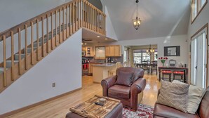 A spacious living area with a wooden staircase, a leather armchair, a sofa, and a coffee table. - Deck, Pool, Trails Access: Pocono Family Home! (Albrightsville)