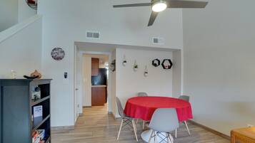 A dining area with a red tablecloth, a ceiling fan, and a bookshelf.