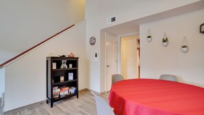 A room with a staircase, a red table, a bookshelf, and a door leading to another room. - Flagstaff Townhome w/ Grill ~ 3 Mi to Downtown! (Flagstaff)