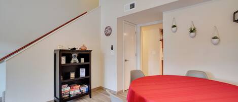 A room with a staircase, a red table, a bookshelf, and a door leading to another room.
