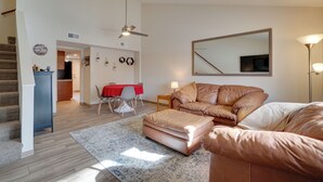 A modern living room with a sofa, ottoman, and a dining area with a red table. - Flagstaff Townhome w/ Grill ~ 3 Mi to Downtown! (Flagstaff)