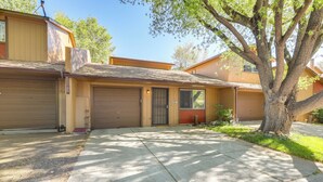 A two-story residential building with a garage, a tree in front, and a clear sky. - Flagstaff Townhome w/ Grill ~ 3 Mi to Downtown! (Flagstaff)