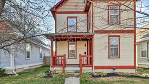 A two-story house with a front porch, a small garden, and a pathway leading to the entrance. - Cozy Indianapolis Home w/ Private Hot Tub! (Indianapolis)