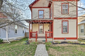 A two-story house with a front porch, a small garden, and a pathway leading to the entrance. - Cozy Indianapolis Home w/ Private Hot Tub! (Indianapolis)