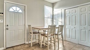 A dining area with a table and four chairs, a white door with a window, and a white door with a panel design. - Cozy Indianapolis Home w/ Private Hot Tub! (Indianapolis)