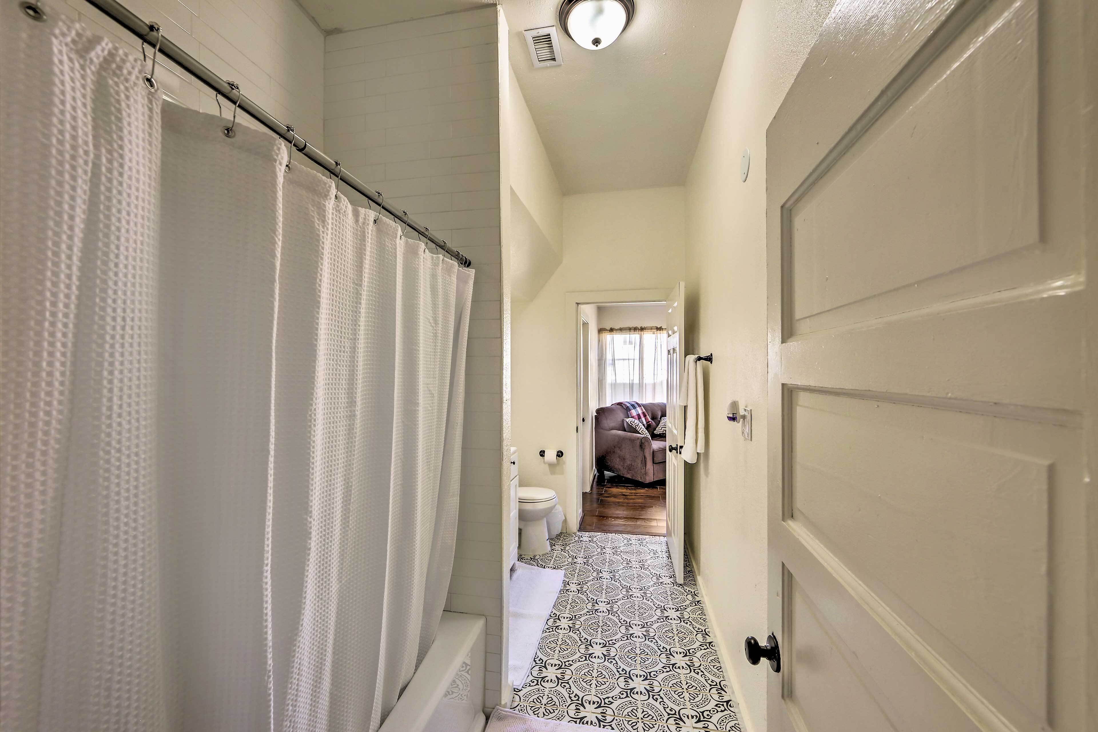 A narrow hallway with a shower curtain, a toilet, and a door leading to another room.