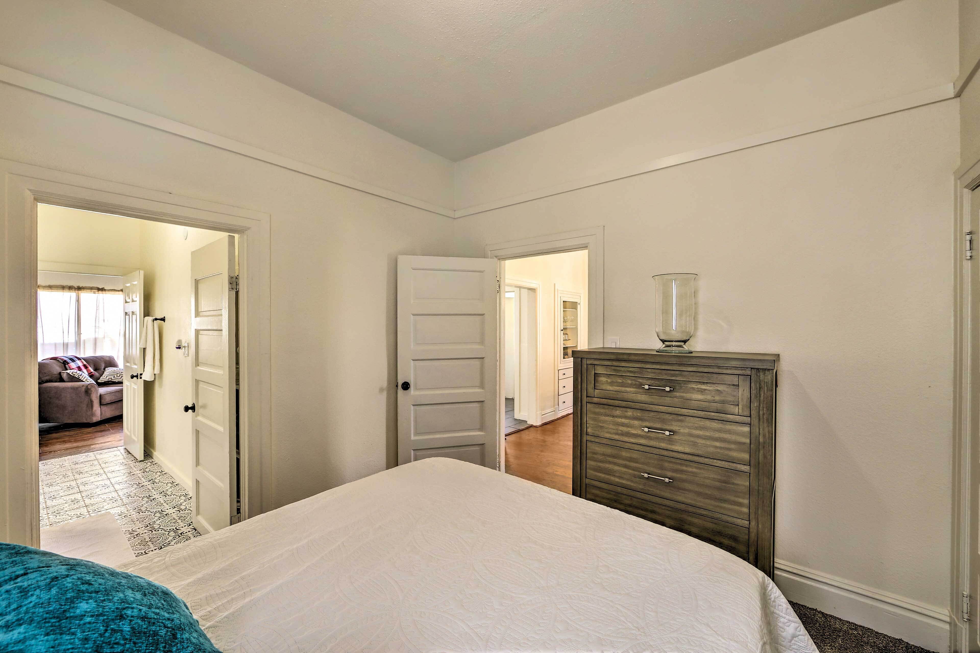 Un dormitorio con cama, cómoda y puerta que da a otra habitación.