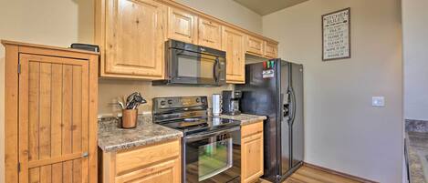 A kitchen with wooden cabinets, a microwave, a refrigerator, and a stove.