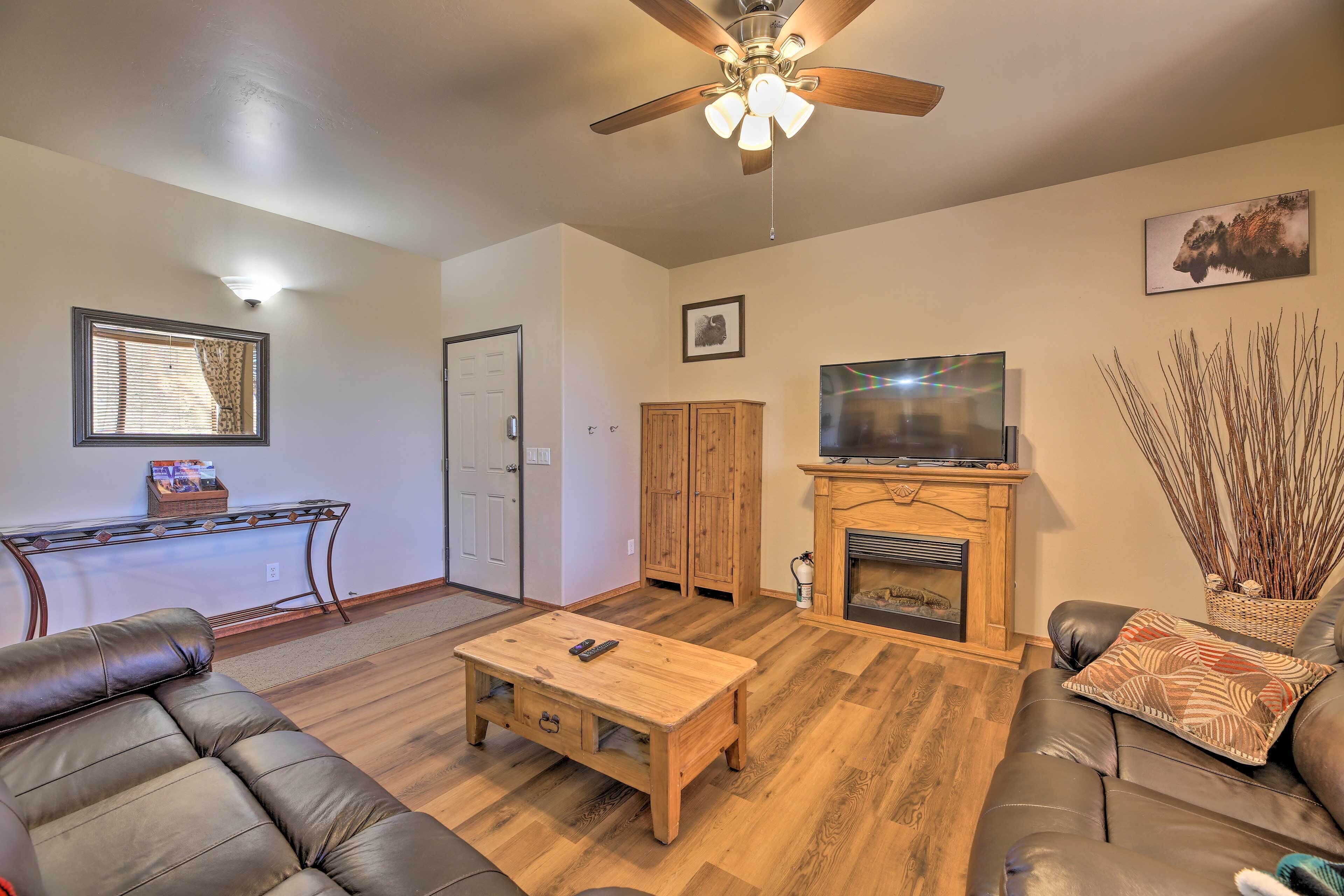 A living room with a sofa, coffee table, TV, fireplace, and wooden cabinets.