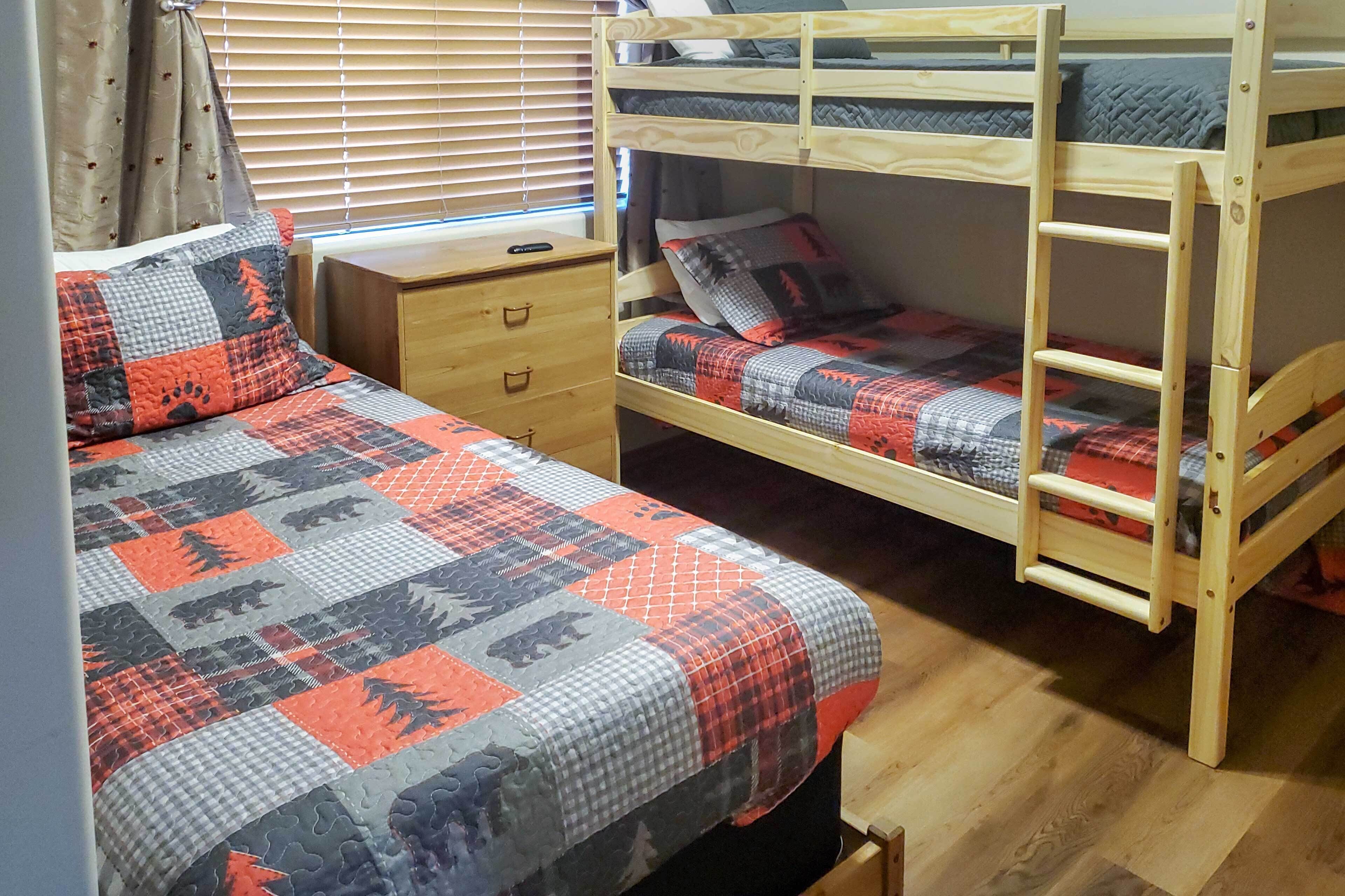 Un lit superposé avec une couvre-lit matelassé et une table de chevet en bois dotée de tiroirs.
