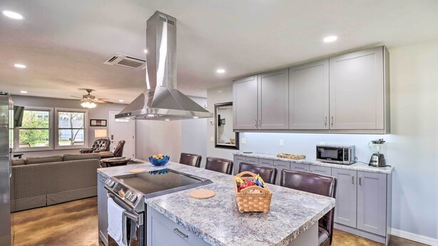 A modern kitchen with a central island, built-in appliances, and grey cabinetry. - Newly Built Cotter Home, Great Fishing Nearby (Cotter)