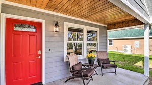 A red door, two windows, a porch with two rocking chairs, a potted plant, and a wooden ceiling. - Newly Built Cotter Home, Great Fishing Nearby (Cotter)