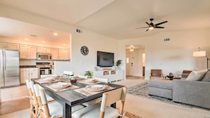 A modern kitchen with stainless steel appliances, a dining area with a dark wooden table and light-colored chairs, and a living room with a gray sofa and a ceiling fan. - Pool Access at Pet-friendly Scottsdale Condo! (Scottsdale)