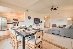 A modern kitchen with stainless steel appliances, a dining area with a dark wooden table and light-colored chairs, and a living room with a gray sofa and a ceiling fan. - Pool Access at Pet-friendly Scottsdale Condo! (Scottsdale)