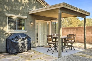 Un patio couvert avec un barbecue, une table et des chaises.