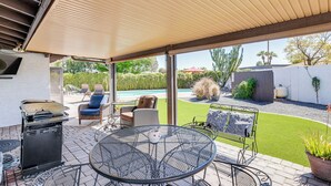 A covered patio area with a grill, outdoor furniture, and a view of a swimming pool and garden. - Private Pool & Grill: Scottsdale Getaway! (Scottsdale)