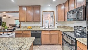 A modern kitchen with granite countertops, wooden cabinets, a dishwasher, a microwave, and an oven. - Private Pool & Grill: Scottsdale Getaway! (Scottsdale)