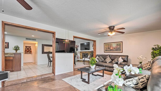 A spacious living room with a leather sofa, a coffee table, and a TV. There is a kitchen area with a dining table and chairs visible through an open doorway. - Private Pool & Grill: Scottsdale Getaway! (Scottsdale)