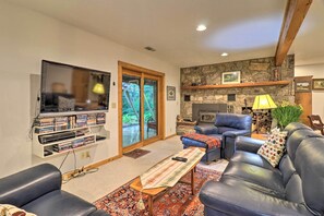 Una sala de estar con chimenea, sofás de cuero, televisor y estantería.