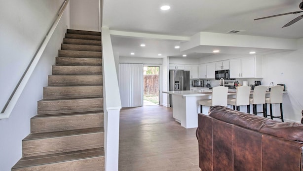 A modern kitchen with white cabinets, a central island, and bar stools.