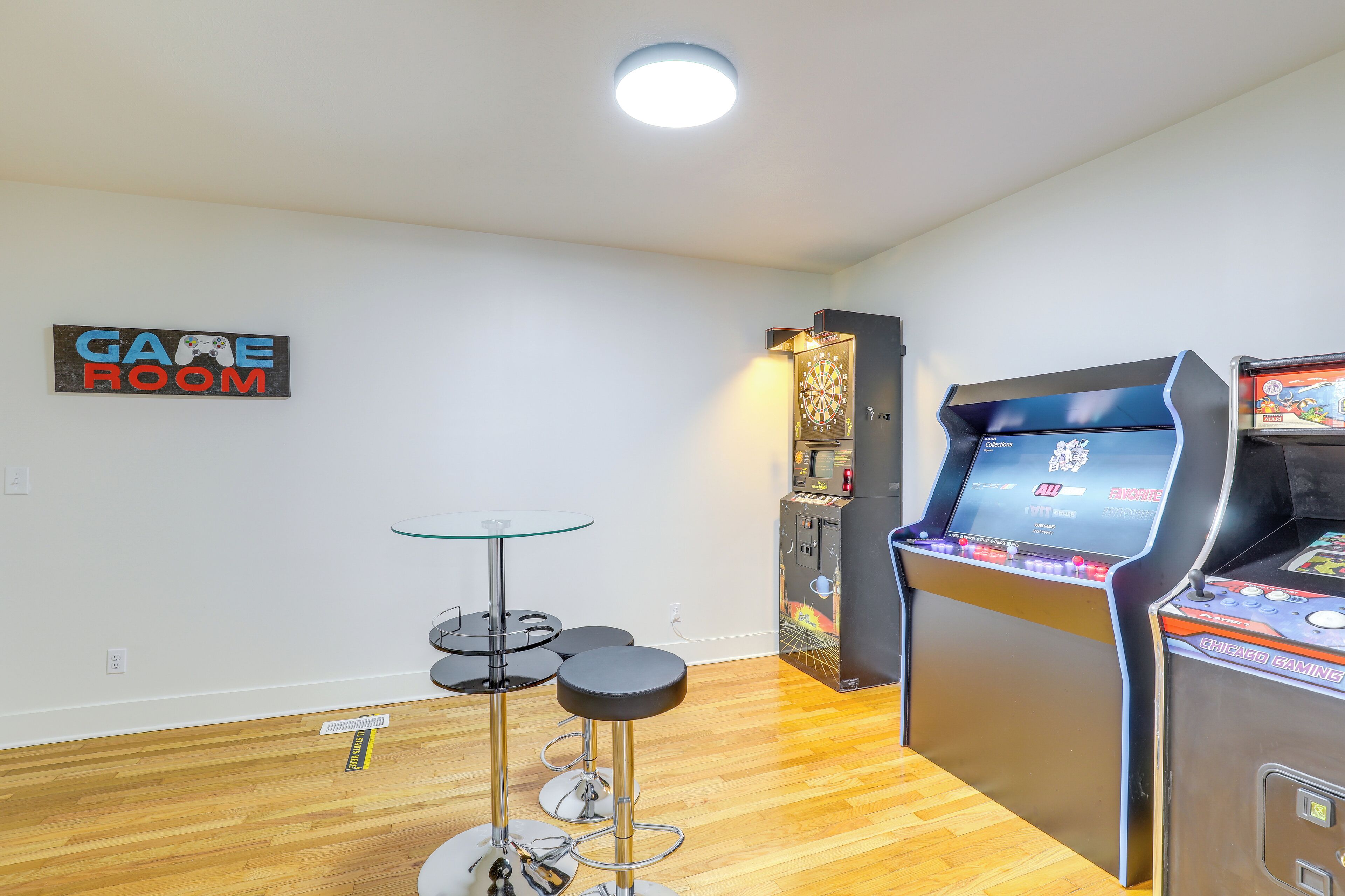 A room with a dartboard, a dart machine, and a sign that reads "GAME ROOM".