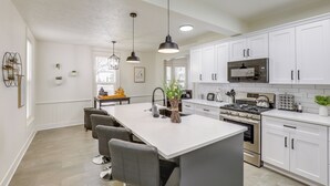 Een moderne keuken met witte kasten, een centraal eiland en hanglampen.