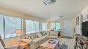A living room with a beige sofa, a wooden coffee table, a brown leather chair, and a television on a wooden stand. - Adobe-style Tumacacori Home w/ Trail Access! (Tumacacori)