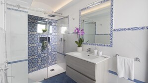 Une salle de bain équipée d’une douche, d’un lavabo, d’un miroir et d’un porte-serviettes.