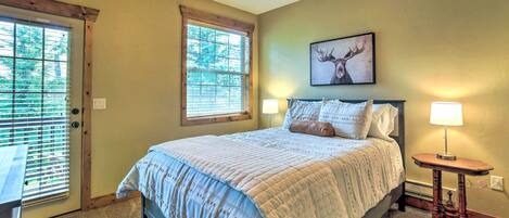 A bedroom with a bed, two bedside lamps, a ceiling fan, a window with blinds, and a framed deer picture on the wall.