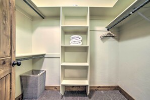 A narrow walk-in closet with a metal basket, a white shelf unit, and a hanging rack. - Cozy Driggs Condo ~ 40 Mi to Grand Teton NP! (Driggs)
