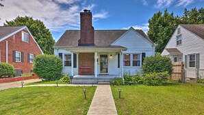 A two-story house with a brick chimney, a front porch, and a well-maintained lawn. - Charming Charleston Home w/ Yard & Fire Pit! (Charleston)
