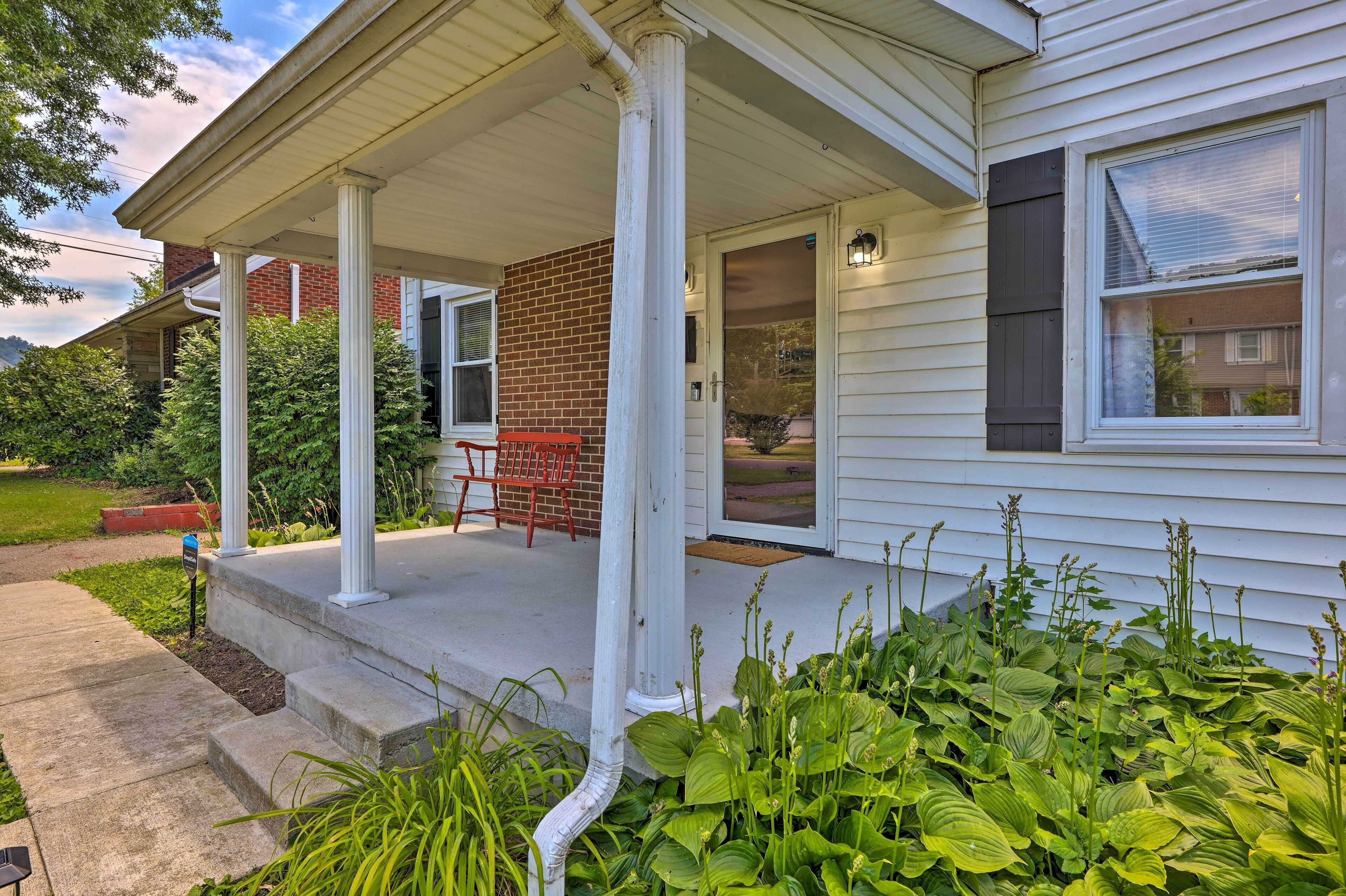 A house with a covered porch, a brick wall, and a red chair.