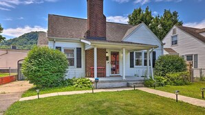 A two-story house with a brick chimney, a porch, and a well-maintained lawn. - Charming Charleston Home w/ Yard & Fire Pit! (Charleston)