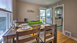 A dining area with a wooden table set for four, a small plant centerpiece, and a wall-mounted sign that reads "Gather". - Charming Charleston Home w/ Yard & Fire Pit! (Charleston)