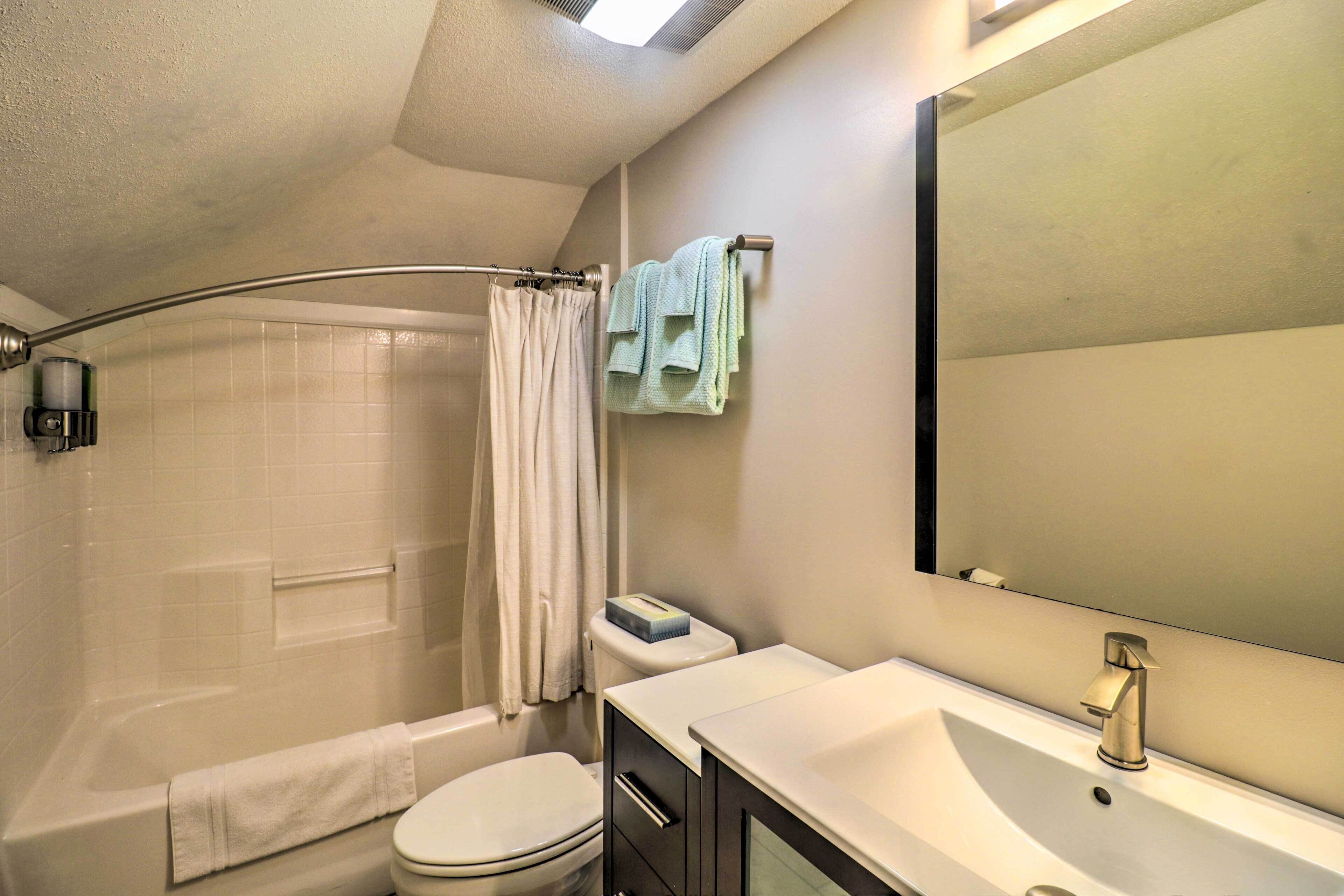 A bathroom with a bathtub, toilet, sink, and a shower curtain.